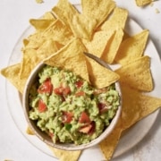 A bowl of 4-ingredient guacamole and chips on a white plate.