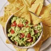 A bowl of 4-ingredient guacamole and chips on a white plate.