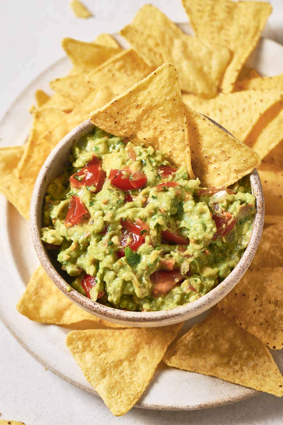 A bowl of 4-ingredient guacamole and chips on a plate.