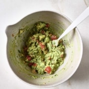 Guacamole in a white bowl with a spoon.