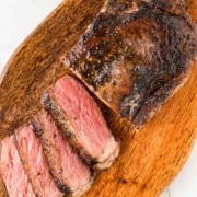 A piece of blackened steak on a wooden cutting board.