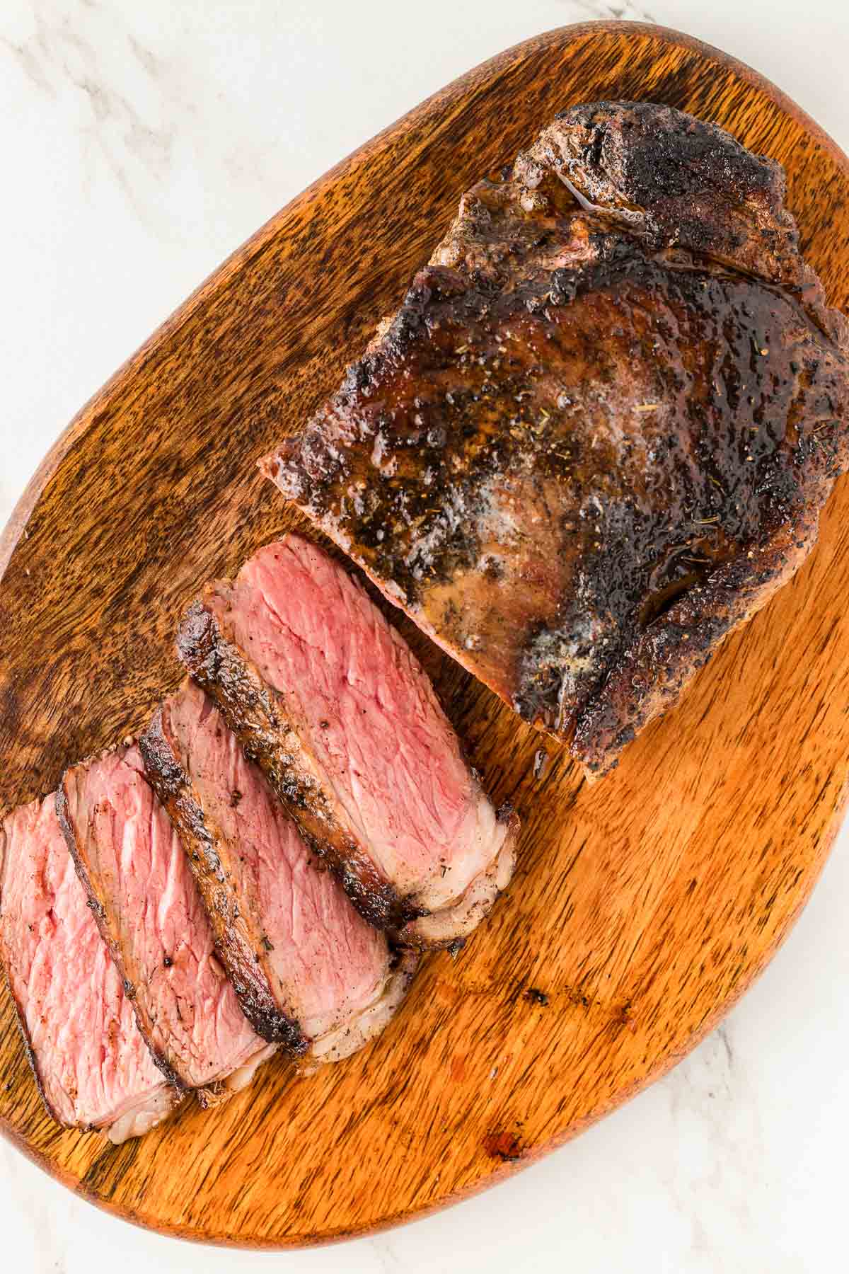 A piece of blackened steak on a wooden cutting board.