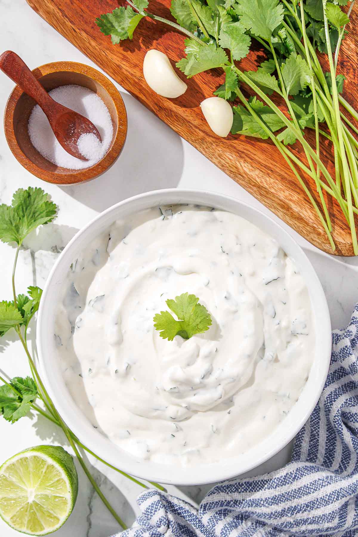 A bowl of creamy cilantro dip with lime, garlic, and salt on a kitchen counter.