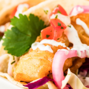 Beer battered fish tacos on a white plate.