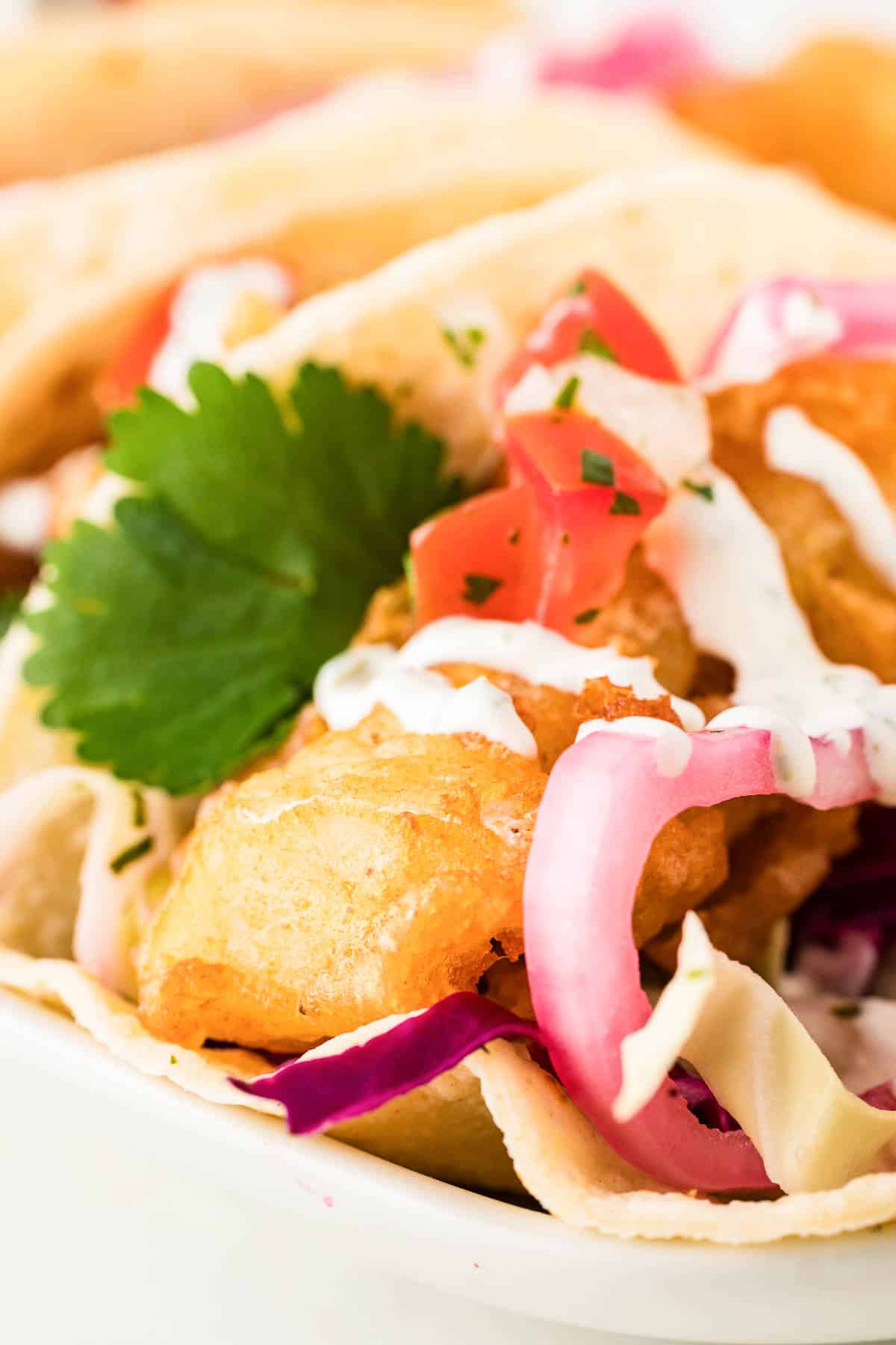 Beer battered fish tacos on a white plate.