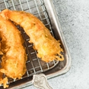Fried battered shrimp on a metal cooling rack with a side of coleslaw.